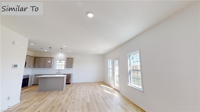 kitchen with light wood finished floors, a center island, light countertops, a sink, and recessed lighting