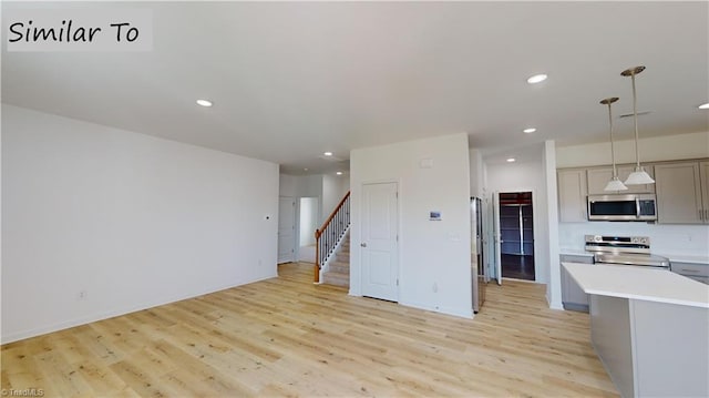 kitchen featuring recessed lighting, open floor plan, light countertops, appliances with stainless steel finishes, and light wood-type flooring