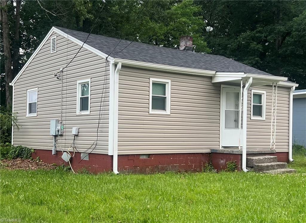 view of side of property featuring crawl space, a yard, a chimney, and a shingled roof