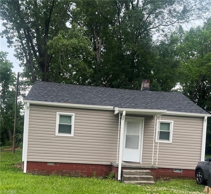 view of front facade featuring crawl space, a chimney, and a shingled roof