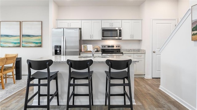 kitchen with white cabinets, stainless steel appliances, and light stone countertops