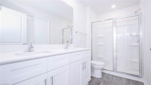 bathroom with hardwood / wood-style floors, vanity, toilet, and walk in shower