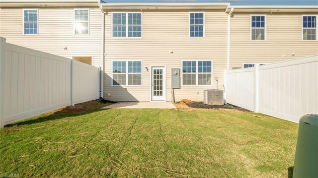 rear view of property featuring a lawn and central AC unit