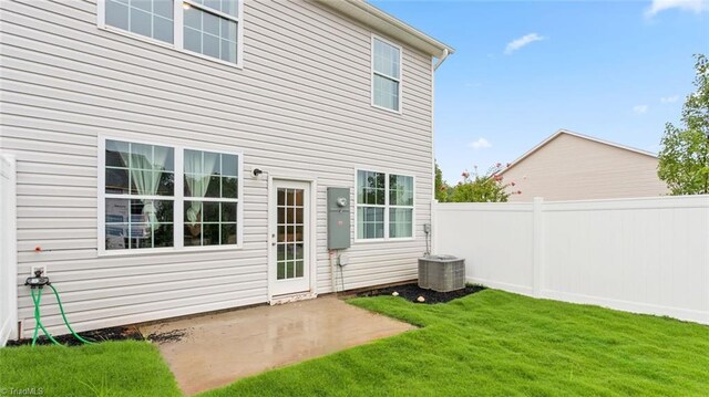 rear view of house with cooling unit, a patio area, and a yard