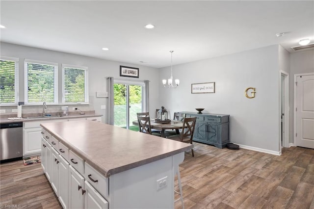 kitchen featuring a kitchen island, dishwasher, white cabinetry, hardwood / wood-style floors, and decorative light fixtures