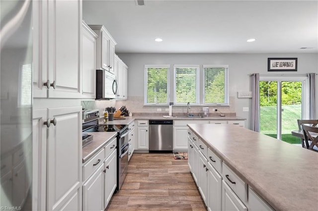 kitchen with backsplash, light hardwood / wood-style flooring, stainless steel appliances, and white cabinetry