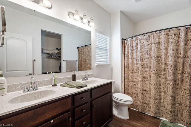 bathroom with hardwood / wood-style flooring, toilet, and double vanity