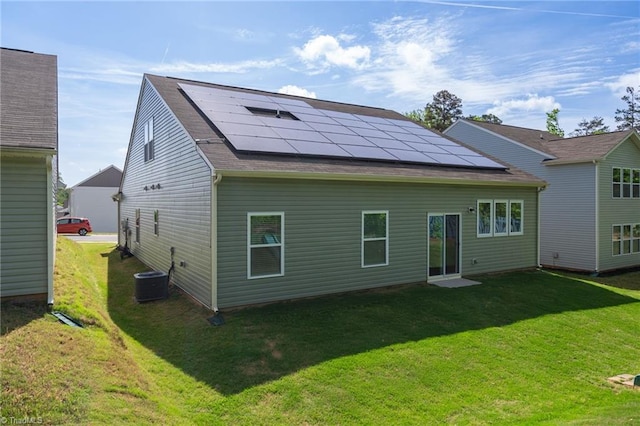 rear view of property featuring solar panels, a yard, and central air condition unit