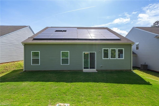 rear view of house featuring solar panels, a yard, and central air condition unit