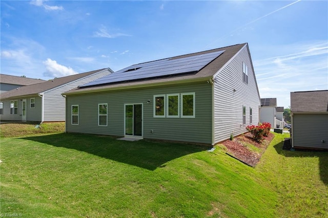 rear view of property with a yard and solar panels