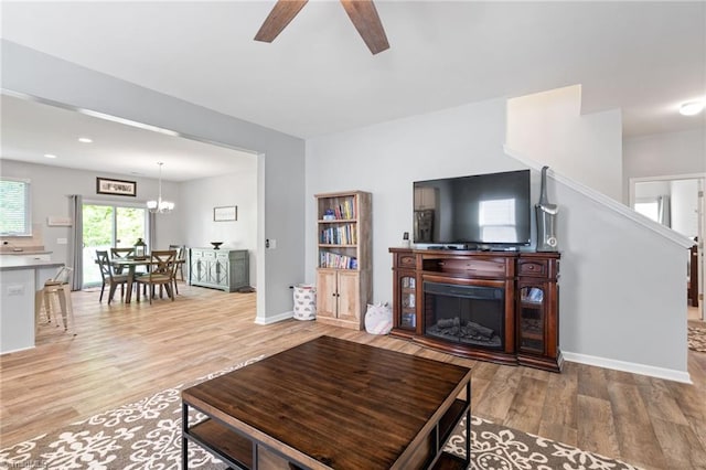 living room featuring wood-type flooring and ceiling fan with notable chandelier