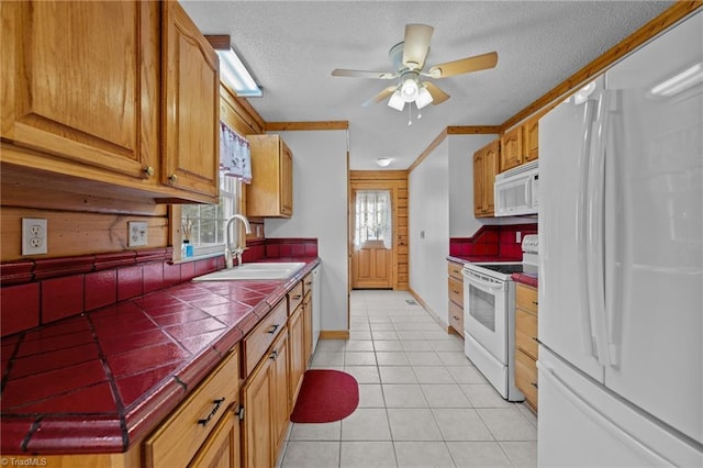 kitchen with tile countertops, sink, white appliances, light tile patterned floors, and a textured ceiling