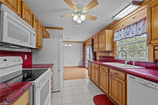 kitchen with sink, white appliances, light tile patterned floors, backsplash, and tile counters