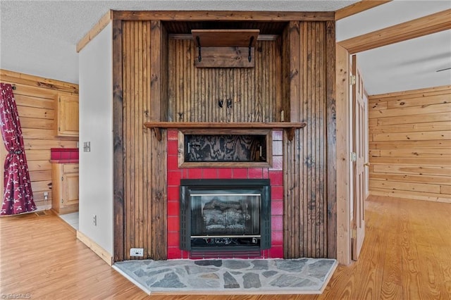 room details featuring hardwood / wood-style flooring, wooden walls, and a tiled fireplace