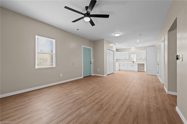 unfurnished living room featuring ceiling fan and light hardwood / wood-style flooring