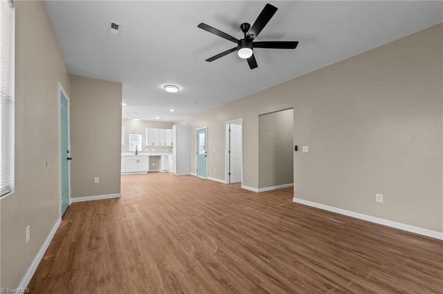 unfurnished living room featuring ceiling fan, sink, and hardwood / wood-style floors