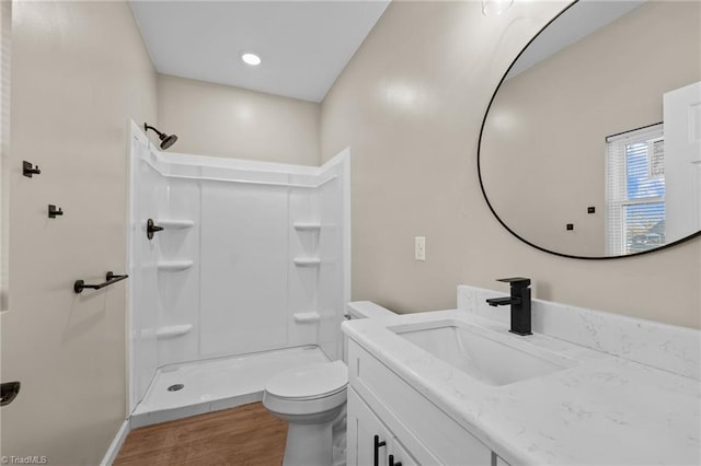 bathroom with hardwood / wood-style flooring, a shower, vanity, and toilet