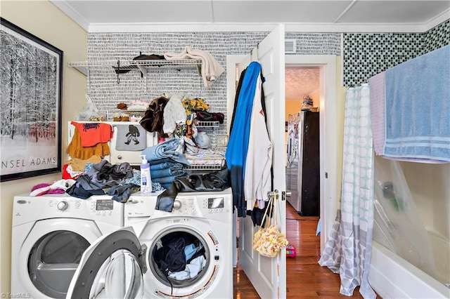 laundry area with dark hardwood / wood-style floors, washing machine and dryer, and crown molding