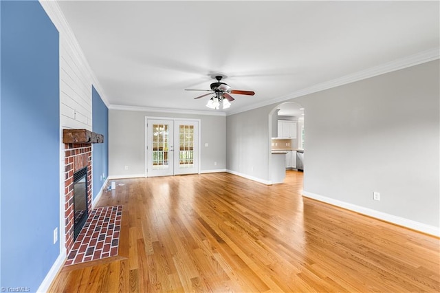 5119 Spiral Wood Dr, Clemmons, NC 27012 - unfurnished living room with ceiling fan, crown molding, a brick fireplace, arched walkways, and light wood-style flooring