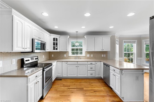 5119 Spiral Wood Dr, Clemmons, NC 27012 - kitchen featuring appliances with stainless steel finishes, a peninsula, healthy amount of natural light, white cabinets, and ornamental molding