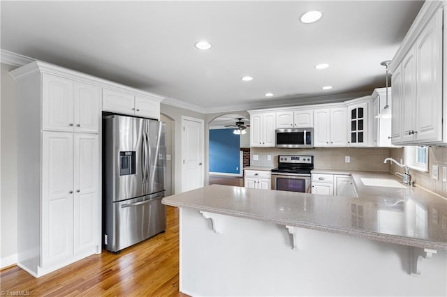 5119 Spiral Wood Dr, Clemmons, NC 27012 - kitchen featuring appliances with stainless steel finishes, a peninsula, a ceiling fan, a kitchen bar, and crown molding