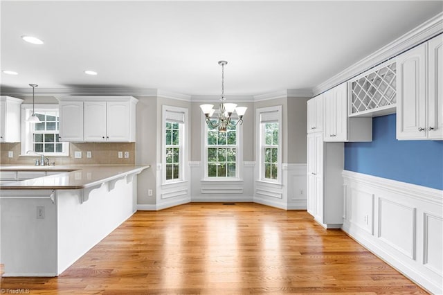 5119 Spiral Wood Dr, Clemmons, NC 27012 - kitchen featuring light wood-type flooring, a chandelier, a kitchen breakfast bar, white cabinets, and pendant lighting