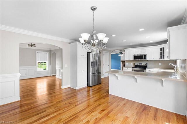 5119 Spiral Wood Dr, Clemmons, NC 27012 - kitchen with stainless steel appliances, a peninsula, a breakfast bar, arched walkways, and white cabinetry