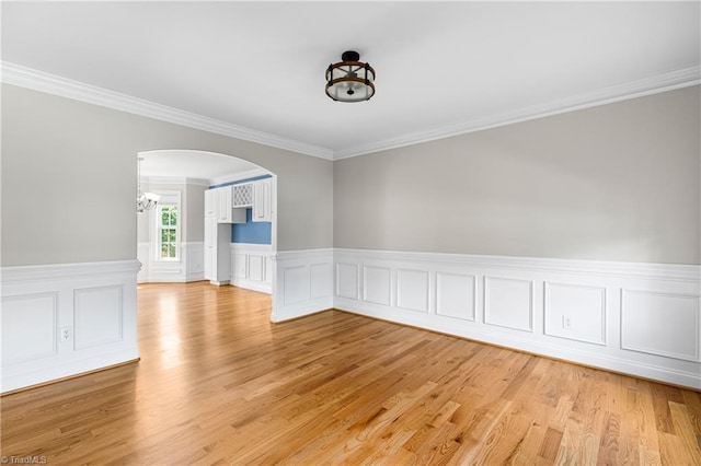5119 Spiral Wood Dr, Clemmons, NC 27012 - unfurnished room with crown molding, arched walkways, light wood finished floors, a wainscoted wall, and a chandelier