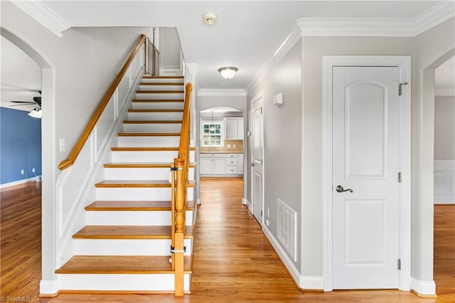 5119 Spiral Wood Dr, Clemmons, NC 27012 - stairway with arched walkways, ceiling fan, wood finished floors, and crown molding
