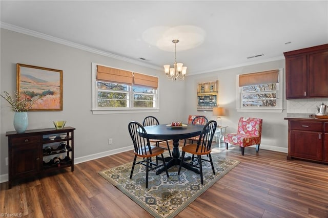 dining area with dark hardwood / wood-style flooring, crown molding, and an inviting chandelier