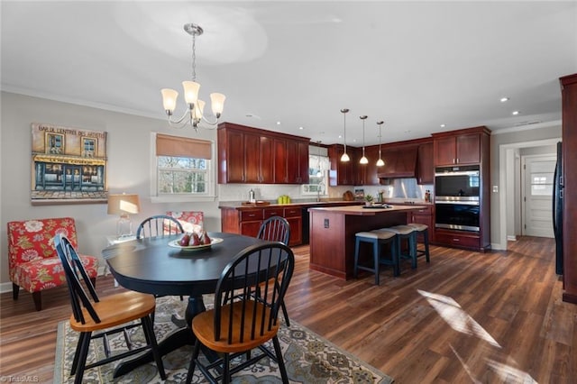 dining area with dark hardwood / wood-style flooring, an inviting chandelier, and ornamental molding