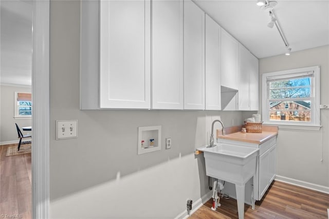 washroom featuring cabinets, washer hookup, track lighting, and hardwood / wood-style floors