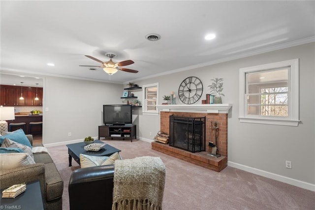 carpeted living room featuring a brick fireplace, ceiling fan, and crown molding