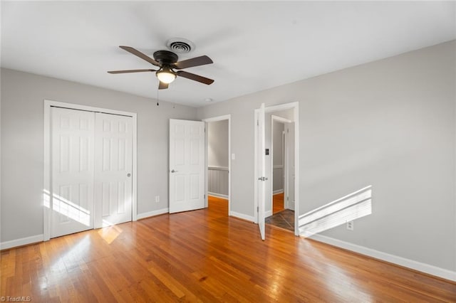 unfurnished bedroom with a closet, hardwood / wood-style flooring, and ceiling fan