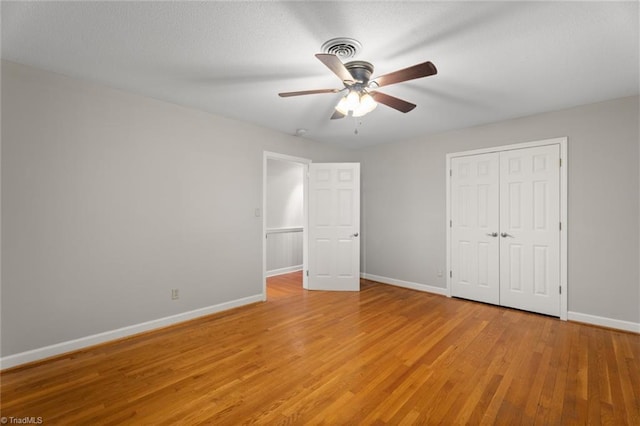 unfurnished bedroom featuring ceiling fan, a closet, and light hardwood / wood-style flooring