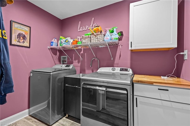 clothes washing area featuring cabinets and washer and clothes dryer