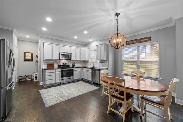 kitchen featuring ornamental molding, dark wood-type flooring, hanging light fixtures, and appliances with stainless steel finishes