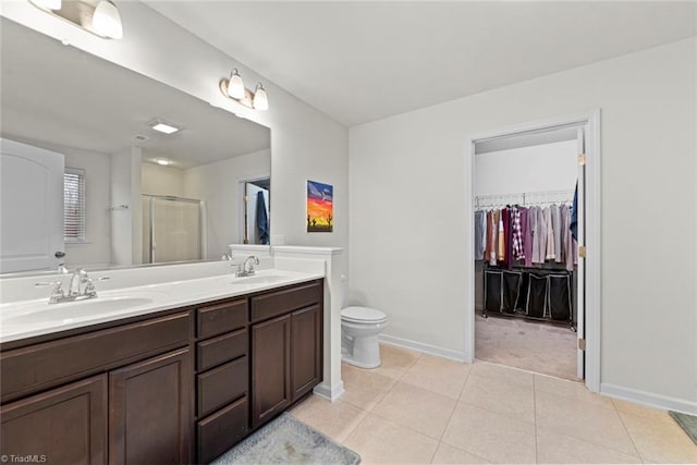 bathroom featuring tile patterned floors, a shower with door, vanity, and toilet