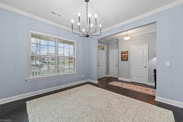 spare room featuring dark hardwood / wood-style flooring, ornamental molding, and an inviting chandelier