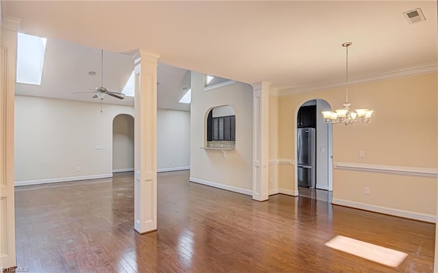 spare room featuring arched walkways, decorative columns, ornamental molding, hardwood / wood-style floors, and ceiling fan with notable chandelier