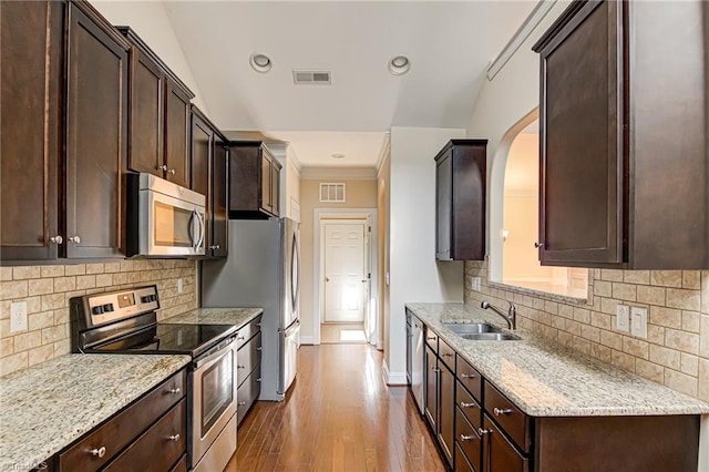 kitchen with appliances with stainless steel finishes, visible vents, a sink, and dark brown cabinets