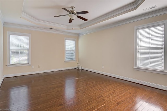 unfurnished room with visible vents, hardwood / wood-style floors, a raised ceiling, and a wealth of natural light