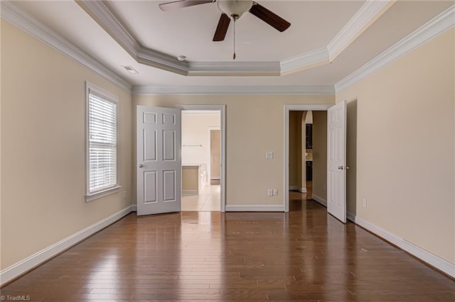 unfurnished bedroom featuring crown molding, a raised ceiling, visible vents, hardwood / wood-style floors, and baseboards