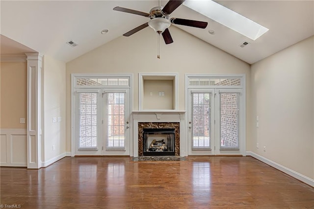 unfurnished living room featuring a healthy amount of sunlight, visible vents, and wood finished floors