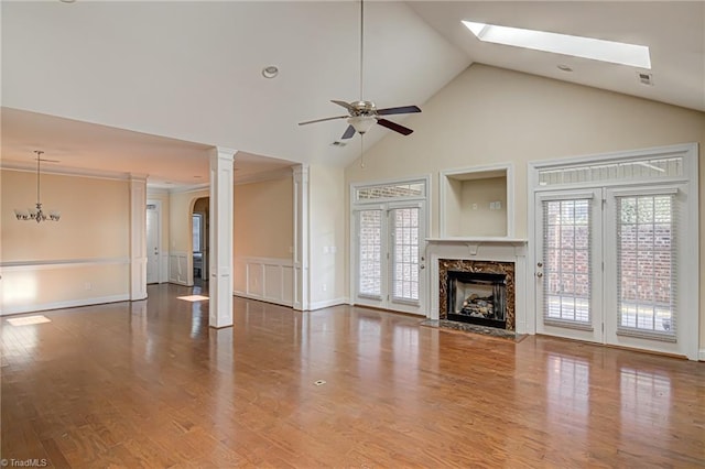 unfurnished living room featuring a healthy amount of sunlight, high vaulted ceiling, wood finished floors, and a high end fireplace