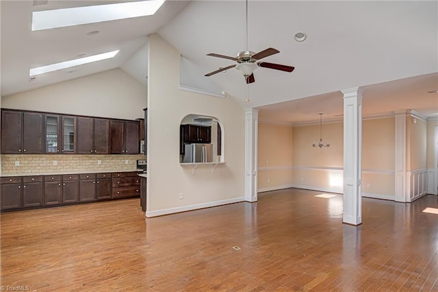 unfurnished living room featuring high vaulted ceiling, light wood-style flooring, a ceiling fan, baseboards, and decorative columns