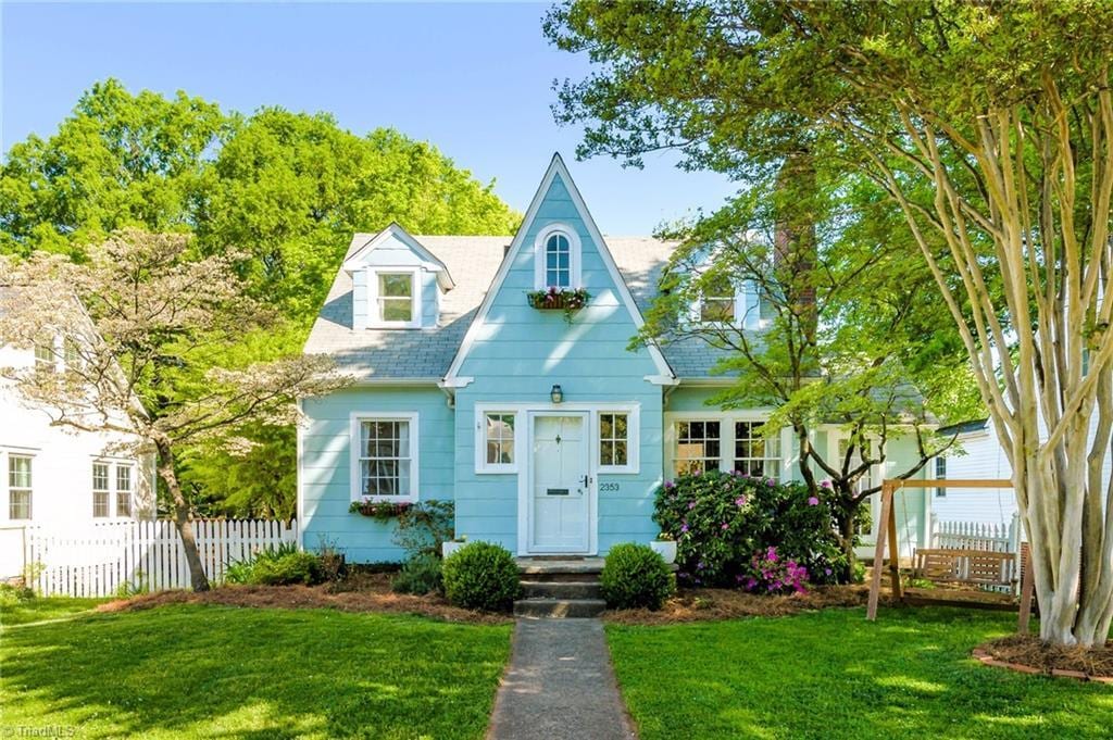 view of front of house featuring fence, roof with shingles, and a front lawn