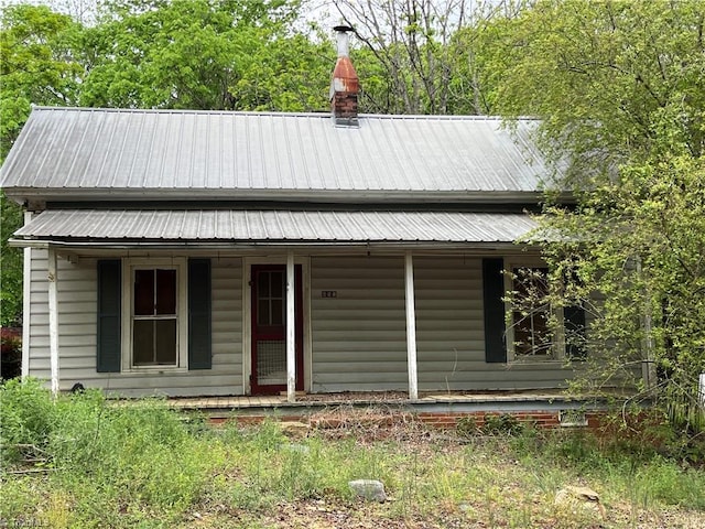 view of front of home featuring a chimney, metal roof, and covered porch