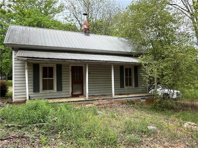 view of front of home with a chimney, metal roof, and covered porch