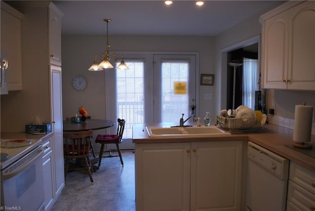 kitchen with white appliances, decorative light fixtures, white cabinetry, sink, and kitchen peninsula